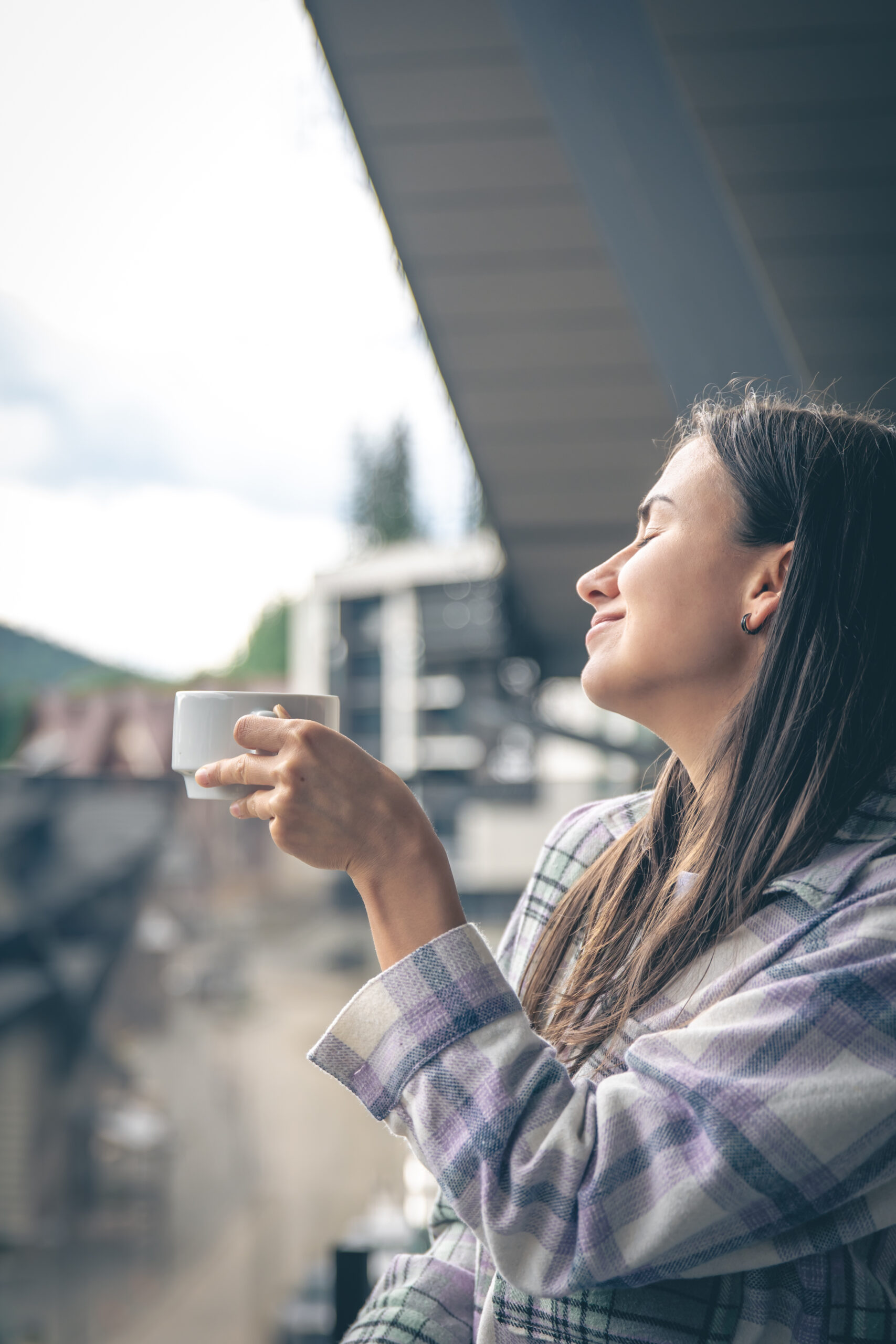 A woman drinking coffee on the balcony in the morning.